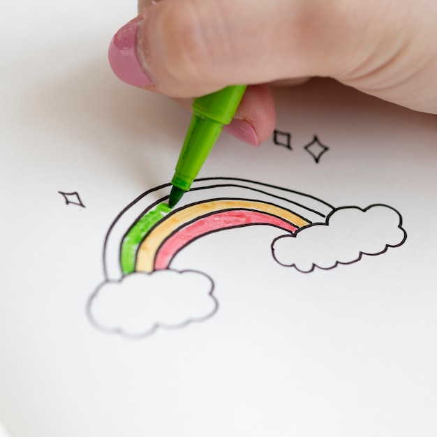 Girl coloring a rainbow doodle in a notebook