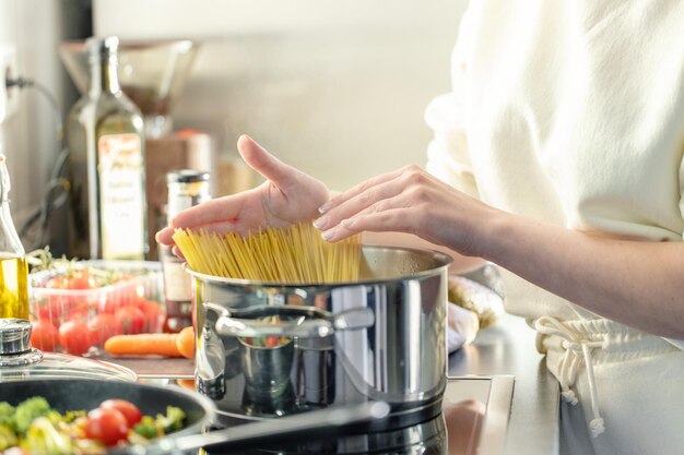Девушка готовит спагетти из макарон в кастрюле