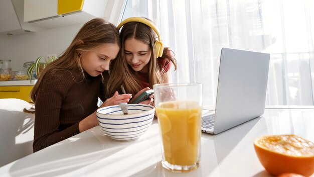 Girl cousins spending time together at home with laptop