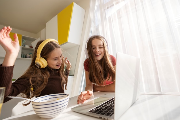 Girl cousins spending time together at home with laptop