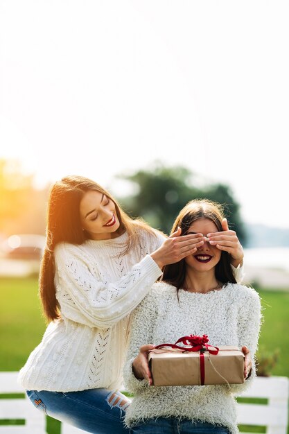 Girl covering eyes with another girl with a gift