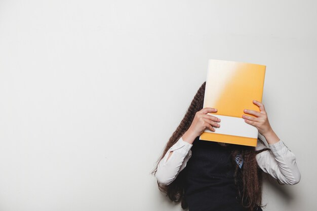 Girl covering face with notebook