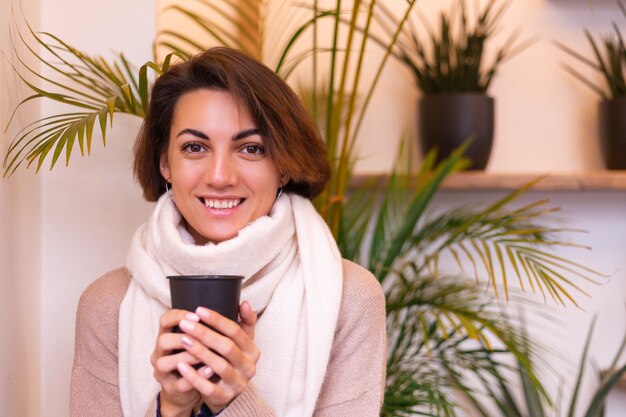 A girl in a cozy cafe warms herself up with a cup of hot coffee