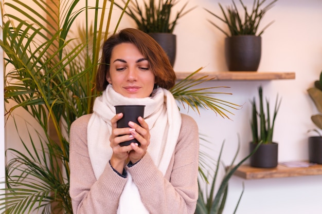 A girl in a cozy cafe warms herself up with a cup of hot coffee