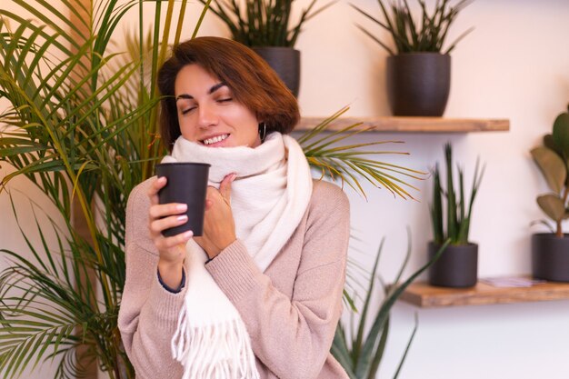 A girl in a cozy cafe warms herself up with a cup of hot coffee