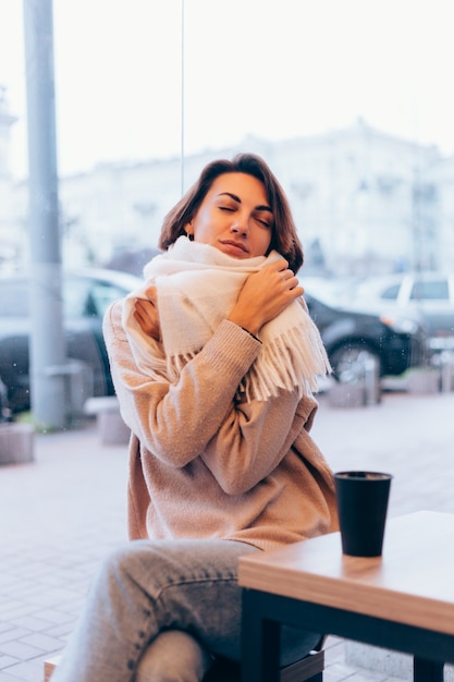 A girl in a cozy cafe warms herself up with a cup of hot coffee