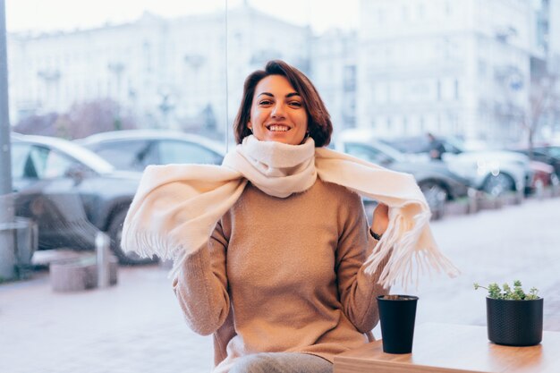 A girl in a cozy cafe warms herself up with a cup of hot coffee