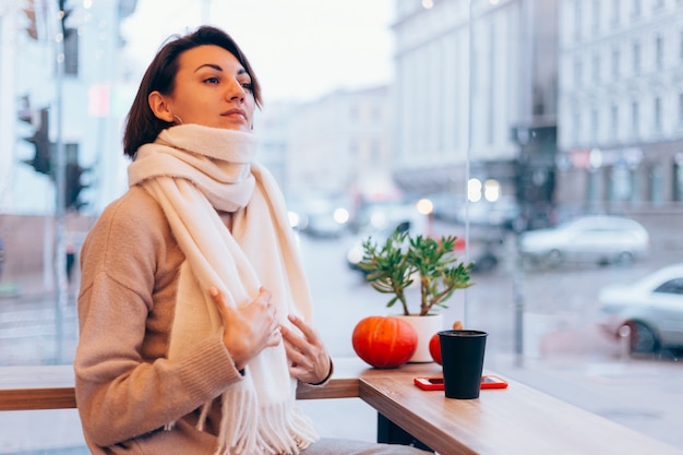 Free photo a girl in a cozy cafe warms herself up with a cup of hot coffee