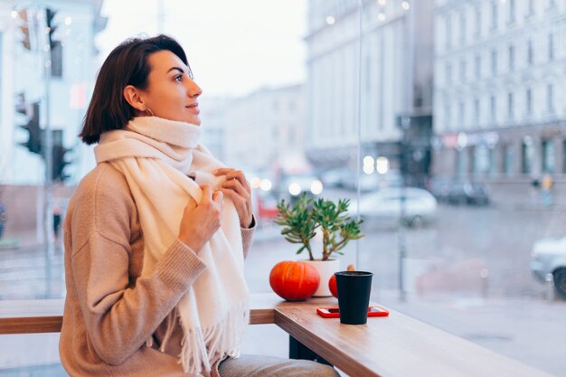 A girl in a cozy cafe warms herself up with a cup of hot coffee