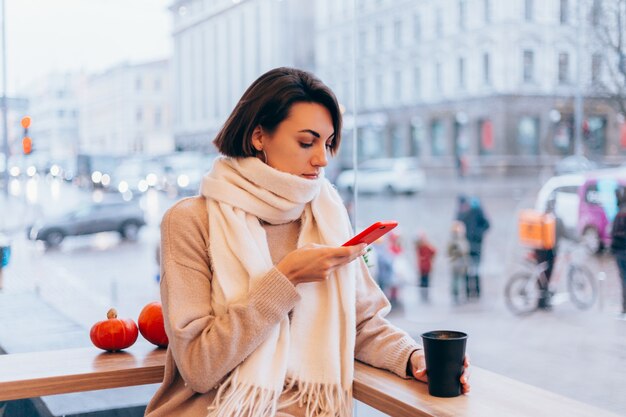 A girl in a cozy cafe warms herself up with a cup of hot coffee