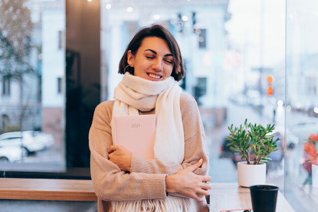 A girl in a cozy cafe warms herself up with a cup of hot coffee