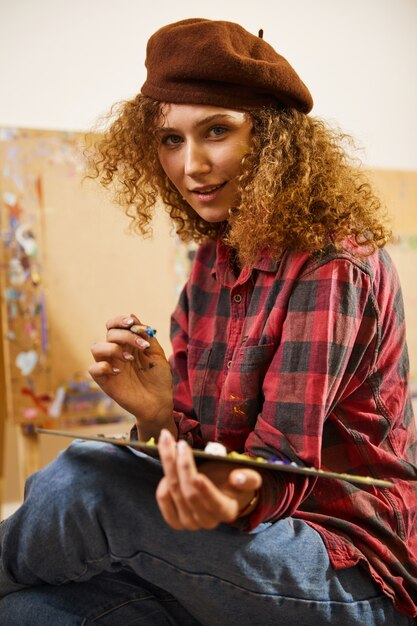 Girl crossed her legs and holds palette with oils