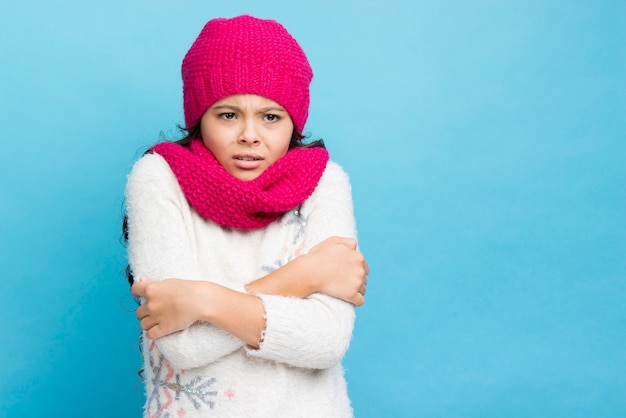 Girl crossing her arms and being cold blue background