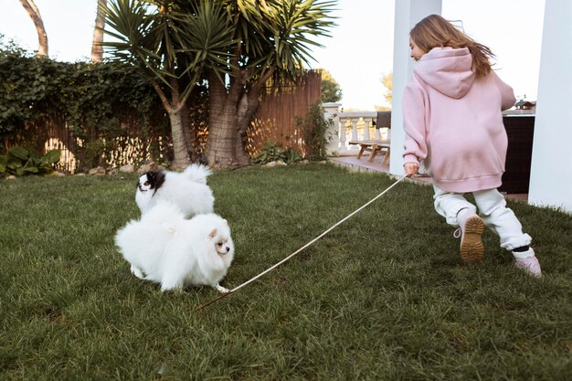 Девочка и милые белые щенки играют в саду