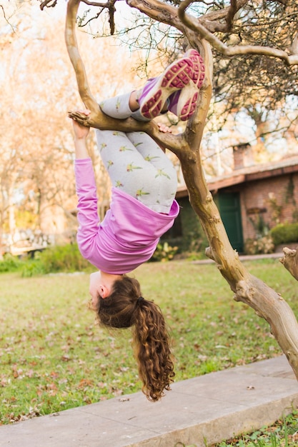 Girl dangling from tree branch in the park