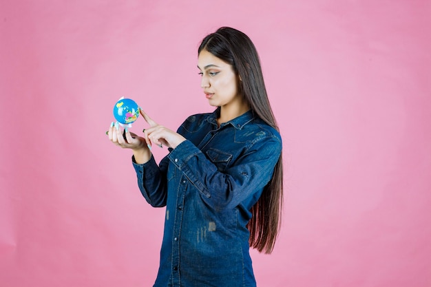 Free photo girl in denim jacket guessing places on the globe