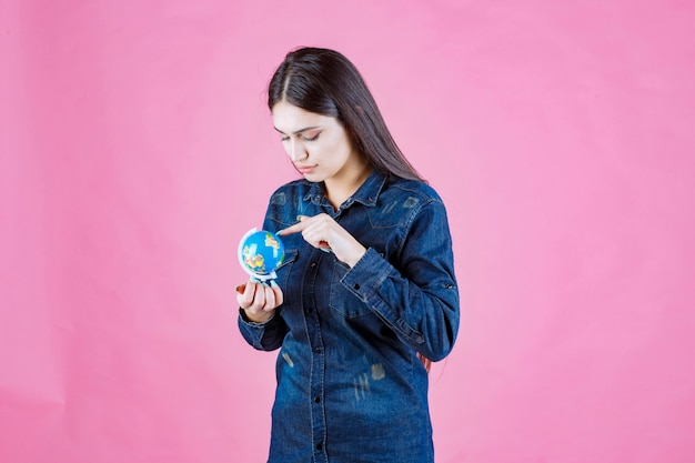 Girl in denim jacket guessing places on the globe