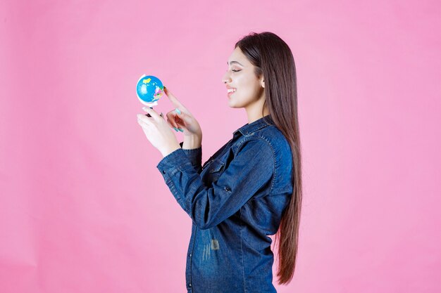 Girl in denim jacket guessing places on the globe