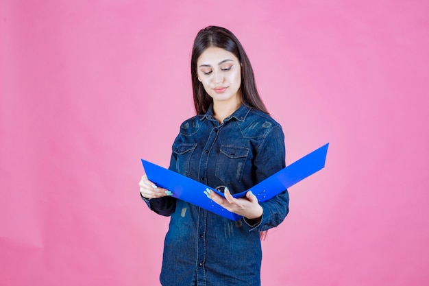 Ragazza in camicia di jeans leggendo i rapporti