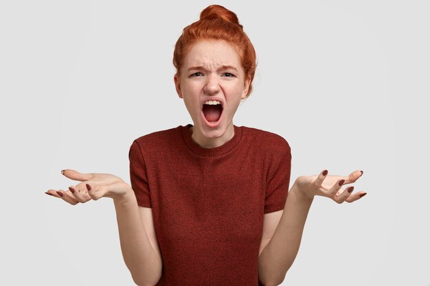 Girl in despair and annoyance. Stressful ginger teenager dressed in casual t shirt, spreads hands