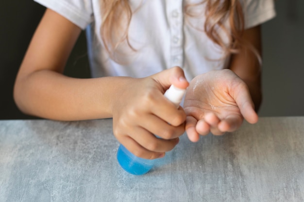 Ragazza che disinfetta le sue mani mentre era seduto alla sua scrivania