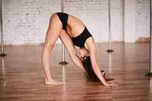 Foto gratuita ragazza fa stretching della schiena prima di un allenamento nella palestra di pole dance