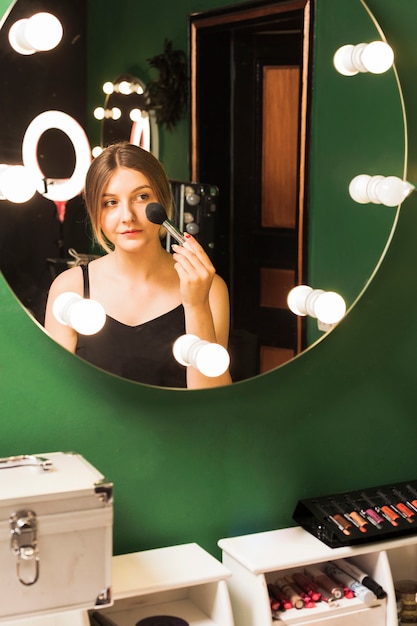 Free photo girl doing her make up in a green room