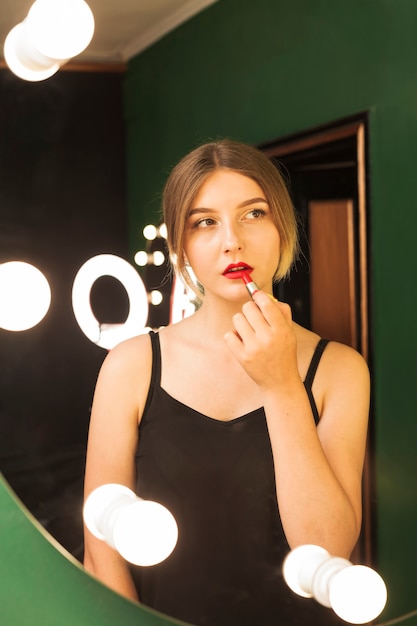 Free photo girl doing her make up in a green room