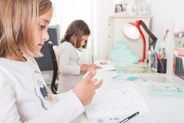 Girl doing homework near sister