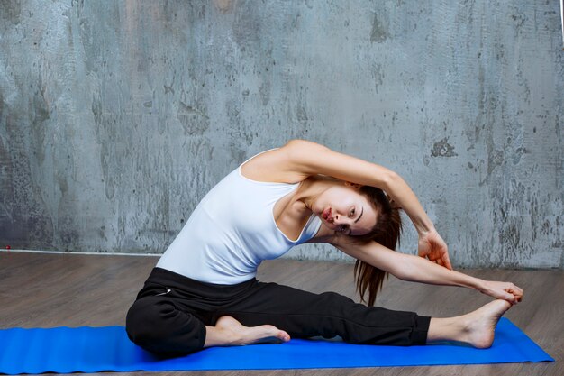 Girl doing leg and back stretching workout in sitting position. 