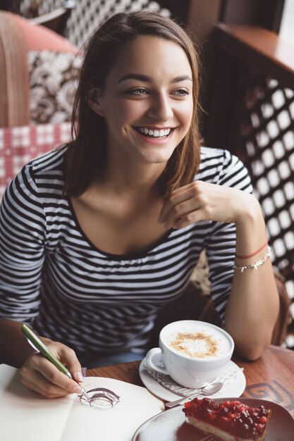 Girl drawing a cup of coffee in the notebook