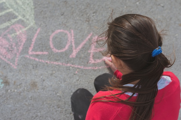 Ragazza che disegna con il gesso sulla strada