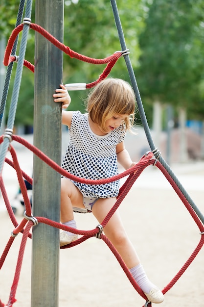 girl in dress climbing on ropes