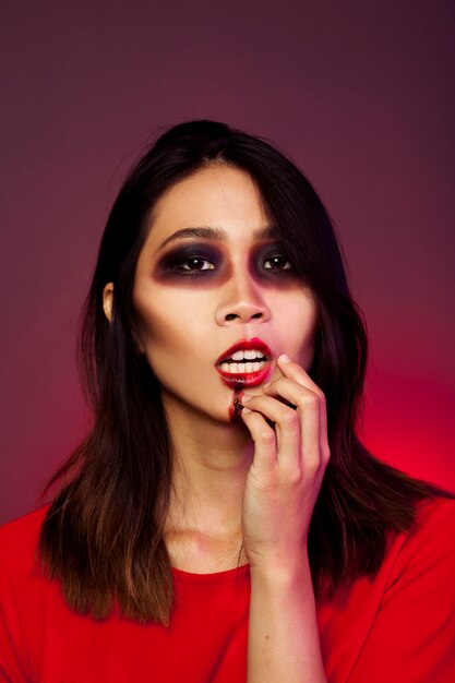 Girl dressed as vampire touching her mouth
