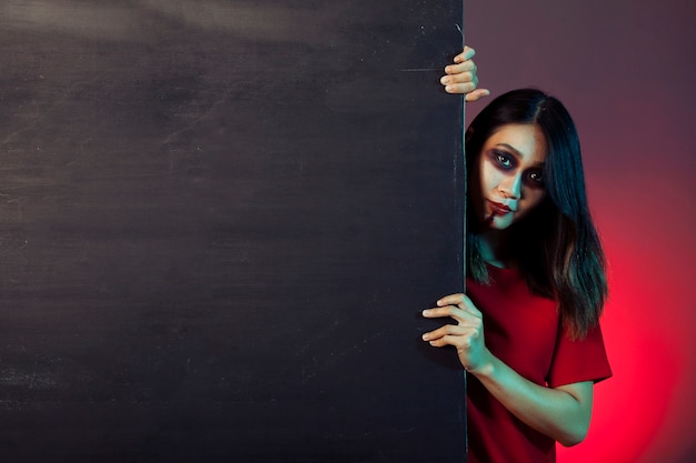 Foto gratuita ragazza vestita come zombie dietro la parete