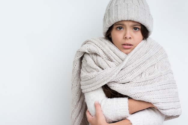 Girl dressed warmly with hands clasped at chest