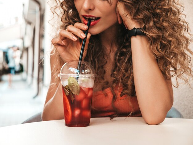 Girl drinking fresh smoothie in plastic cup with straw