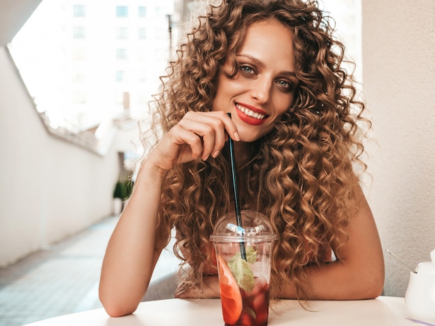 Girl drinking fresh smoothie in plastic cup with straw