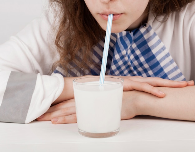 Foto gratuita ragazza che beve latte con una cannuccia di plastica