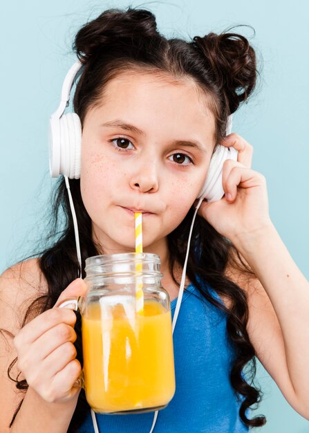 音楽を聴きながらオレンジジュースを飲む女の子