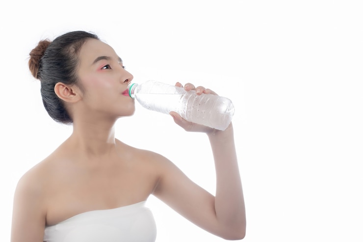 無料Photo 白い背景の上の水を飲む女の子。