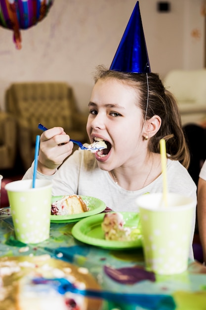 Девушка ест торт на вечеринке по случаю дня рождения