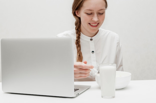 Foto gratuita ragazza che mangia cereale con latte sulla sua scrivania