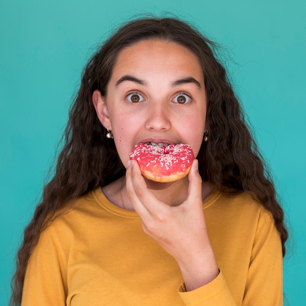 Foto gratuita ragazza che mangia una ciambella deliziosa