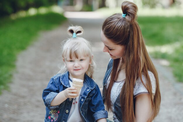 彼女の母親が彼女を見ながら、少女は、アイスクリームを食べます