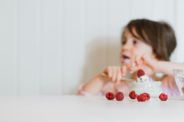 Girl eating raspberry at table