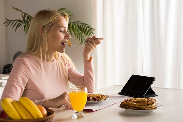 Ragazza che mangia le cialde guardando tablet