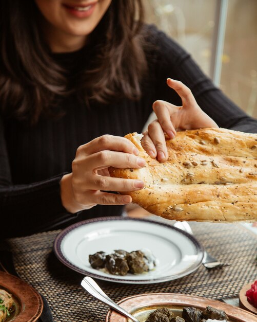  a girl eats dolma with yogurt and tears a piece of bread