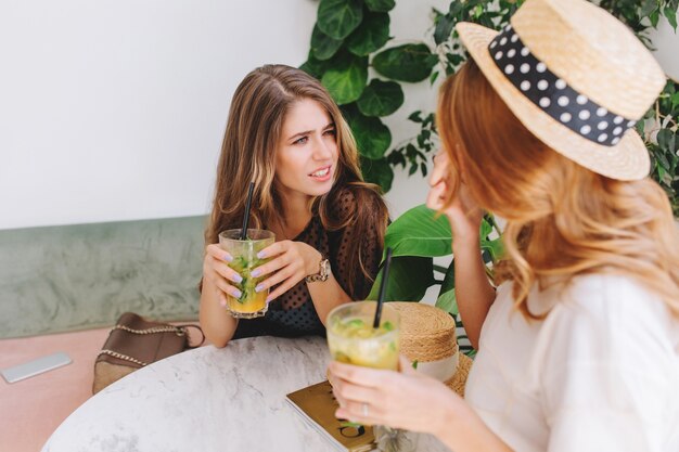 Girl in elegant wristwatch listening friend with incredulous face expression