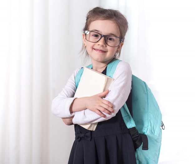 Studente della scuola elementare con uno zaino e un libro